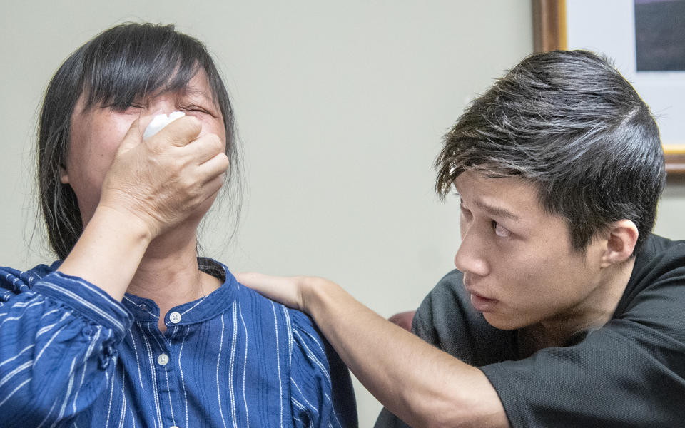 Yingying Zhang's mother, Lifeng Ye, is comforted by Yingying's brother Zhengyang Zhang, during a press conference at lawyer Steve Beckett's law office on Wednesday, August 7 2019 Urbana, Ill. The father of the slain scholar who begged his daughter's killer to reveal what he did with her remains so that they could be returned to China for burial says his family now understands that recovering them may be impossible. Ronggao Zhang said Wednesday that one of his lawyers explained that Brendt Christensen told his defense team he had divided Yingying Zhang's remains into three garbage bags that he threw into a dumpster before the dumpster's contents were compacted and buried in a landfill. (Robin Scholz/The News-Gazette via AP )