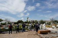 People wearing protective face masks pray in front of the coffin of a person who died of coronavirus disease (COVID-19), at the Spanish muslim military cemetery, in Grinon