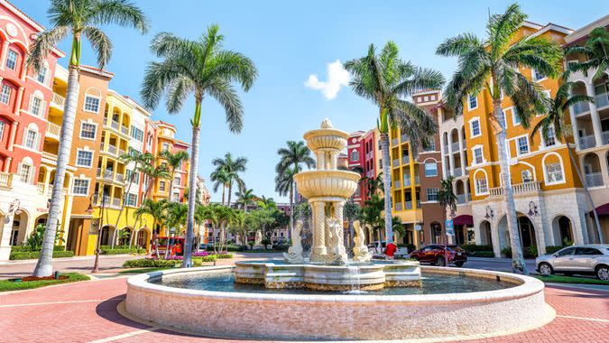 Naples, USA - April 30, 2018: Bayfront condos, condominiums colorful, multicolored, multi-colored buildings with fountain, water, palm trees, blue sky in residential community.