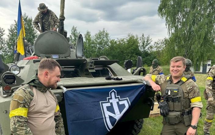 Members of Russian Volunteer Corps stand next to an armoured vehicle in this undated handout picture obtained by Reuters on May 23, 2023. - Russian Volunteer Corps handout/via Reuters