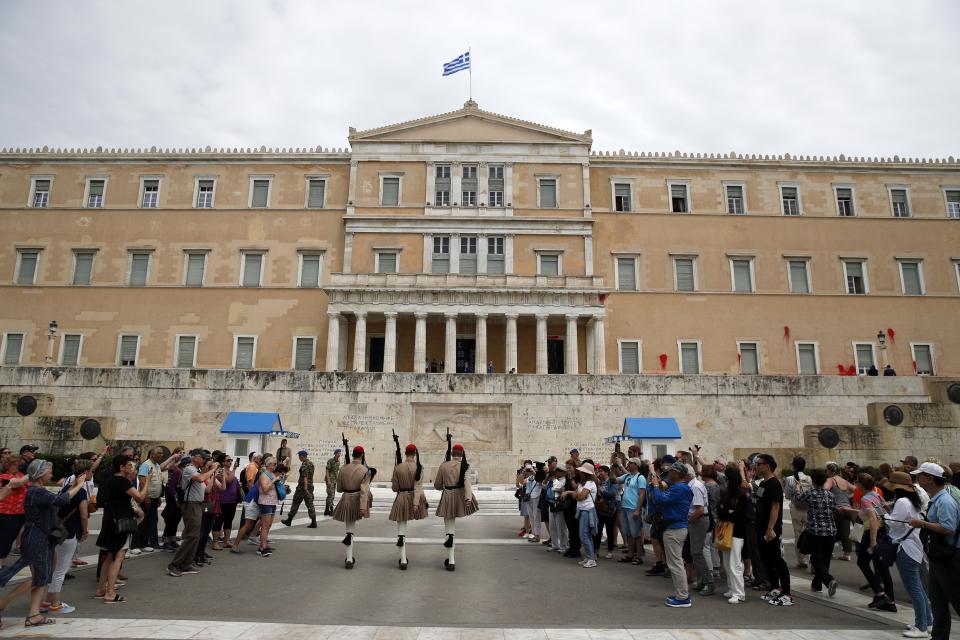 Red paint is seen on the wall of the Parliament building during Greek Presidential changing of the guard, at the tomb of the unknown Soldier in Athens, Tuesday, May 21, 2019. A group of about 10 people threw red paint at parliament and set off a smoke bomb as Greece's Supreme Court heard an appeal against the denial of a temporary leave of absence from prison of a hunger striking extremist serving multiple life sentences for the killings of 11 people by the country's deadliest far-left group. (AP Photo/Thanassis Stavrakis)