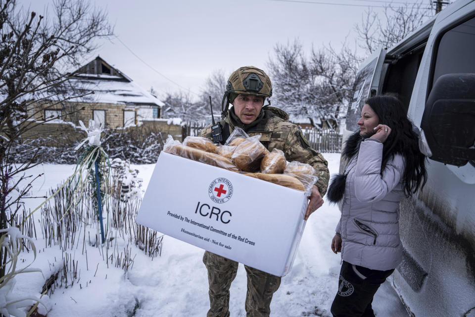 A Ukrainian police officer of the White Angels unit, distributes humanitarian aid to a local volunteer in Krasnohorivka, Ukraine, Friday, Feb. 17, 2023. For months, authorities have been urging civilians in areas near the fighting in eastern Ukraine to evacuate to safer parts of the country. But while many have heeded the call, others -– including families with children -– have steadfastly refused. (AP Photo/Evgeniy Maloletka)