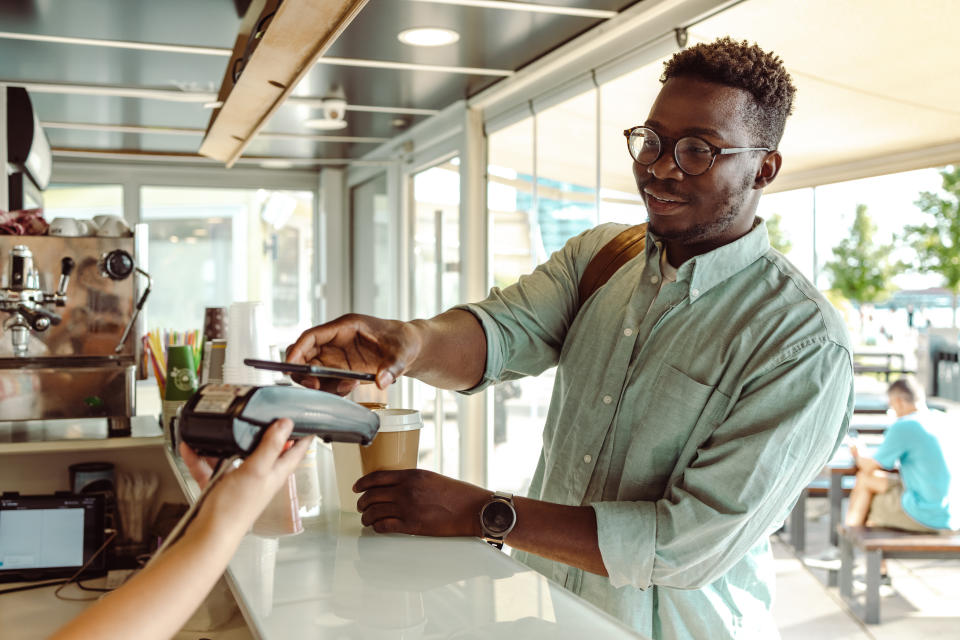 Man paying with smartphone at a coffee shop counter