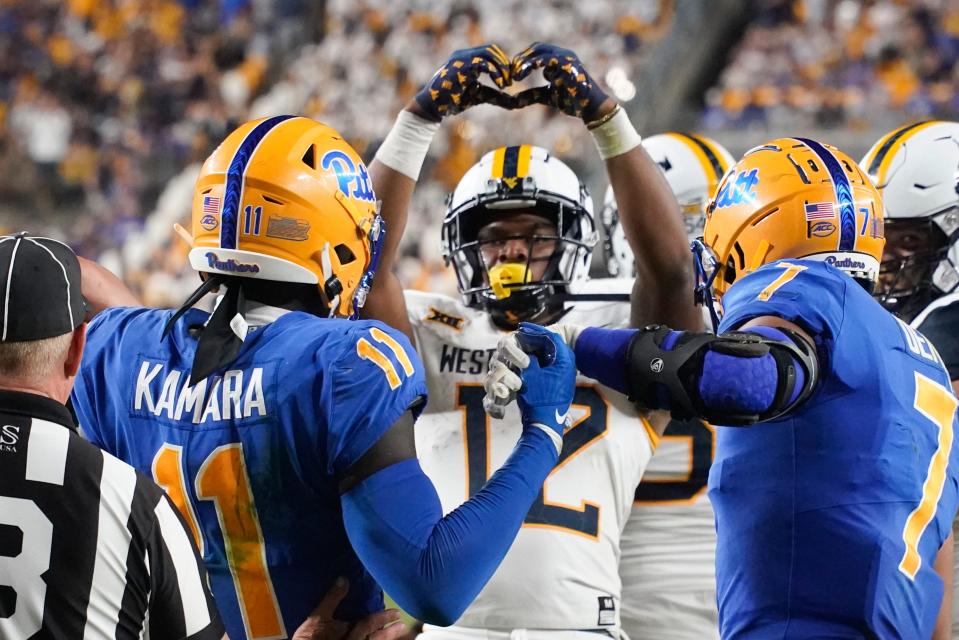 West Virginia's CJ Donaldson (12) celebrates in front of Pittsburgh's Bangally Kamara (11) and SirVocea Dennis (7) after scoring a touchdown during the second half of a Sept. 1 game in Pittsburgh.