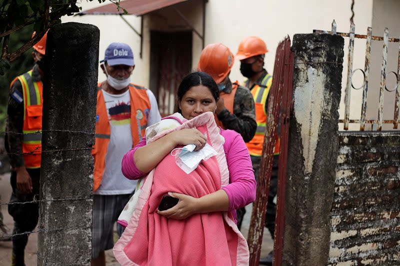 Una mujer que carga a su hijo sale de su casa mientras los soldados hondureños evacúan a los residentes en previsión de las fuertes lluvias que se avecinan con el huracán Iota, en Marcovia