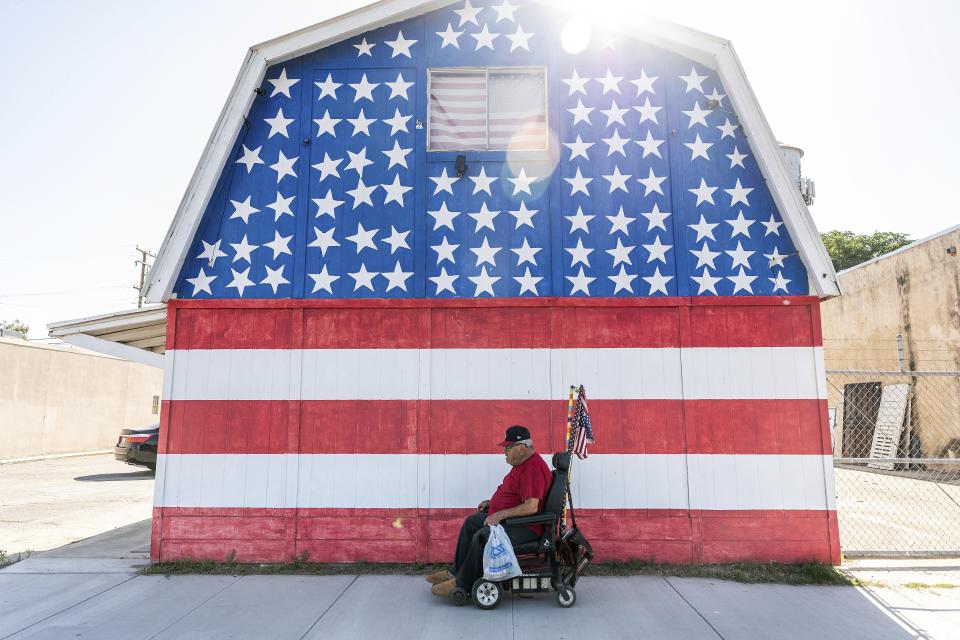 A man passes a building on Main St. n Pixley, Calif, on Tuesday, May 21, 2024, Some residents say dairies located throughout the region produce air pollution that is hurting their community. (AP Photo/Noah Berger)