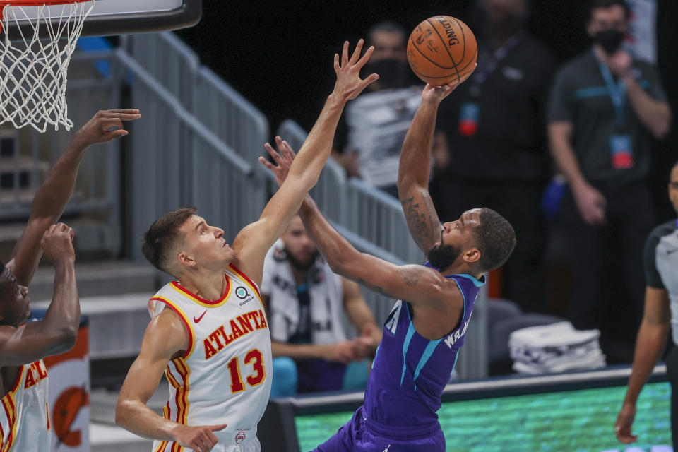 Charlotte Hornets guard Brad Wanamaker, right, shoots over Atlanta Hawks guard Bogdan Bogdanovic, left, during the second quarter of an NBA basketball game in Charlotte, N.C., Sunday, April 11, 2021. (AP Photo/Nell Redmond)