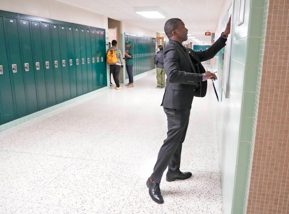 Principal Alonzo Fuller straightens a bulletin board at Milwaukee Public School’s James Madison Academic Campus High School on West Florist Avenue in Milwaukee on Thursday, Nov. 16, 2023. A few weeks ago, there was a large fight at Madison High School which brought police squads from across the city.