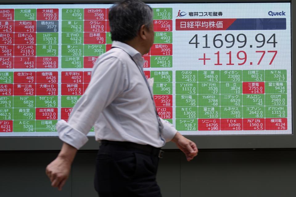 A person walk as he looks at an electronic stock board showing Japan's Nikkei index at a securities firm Wednesday, July 10, 2024, in Tokyo. (AP Photo/Eugene Hoshiko)