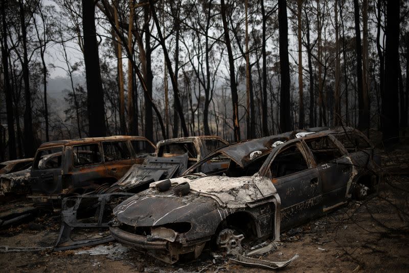 Destroyed cars are seen next to burnt bushland in the village of Mogo