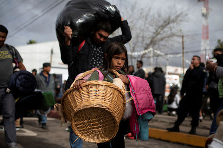 A girl from Honduras and her family, part of a caravan of thousands of migrants from Central America trying to reach the United States, carry their belongings as they leave a temporary shelter in Tijuana, Mexico, November 30, 2018. REUTERS/Alkis Konstantinidis