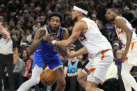 Phoenix Suns guard Devin Booker, center, knocks the ball away from Dallas Mavericks forward Derrick Jones Jr., left, during the first half of an NBA basketball game, Monday, Dec. 25, 2023, in Phoenix. (AP Photo/Rick Scuteri)