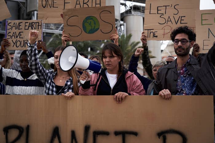 A group of protesters hold up signs about saving the planet and the environment