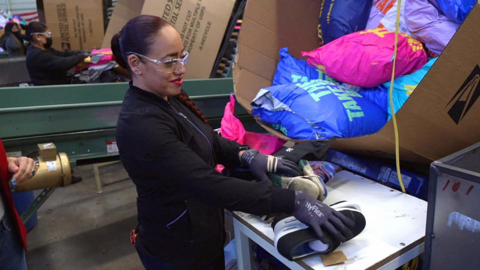 PHOTO: ABC News Chief Meteorologist Ginger Zee examines how donated clothes are processed. (ABC News)