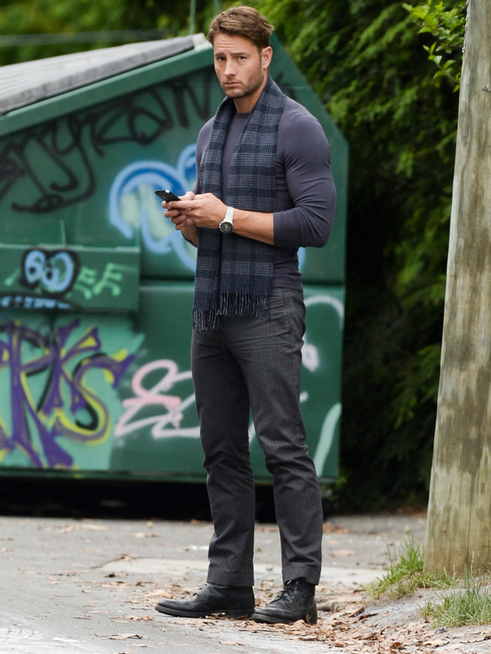 <p>Justin Hartley stops to check his phone while on a break from filming <em>The Noel Diary</em> in Fairfield County, Connecticut on June 13.</p>