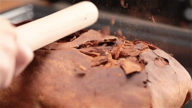 Breaking open crust of Beggar's duck with rolling pin