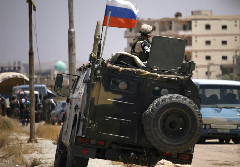 A Russian soldier on his armoured vehicle watches Syrian rebels during an evacuation from Daraa city, on July 15, 2018