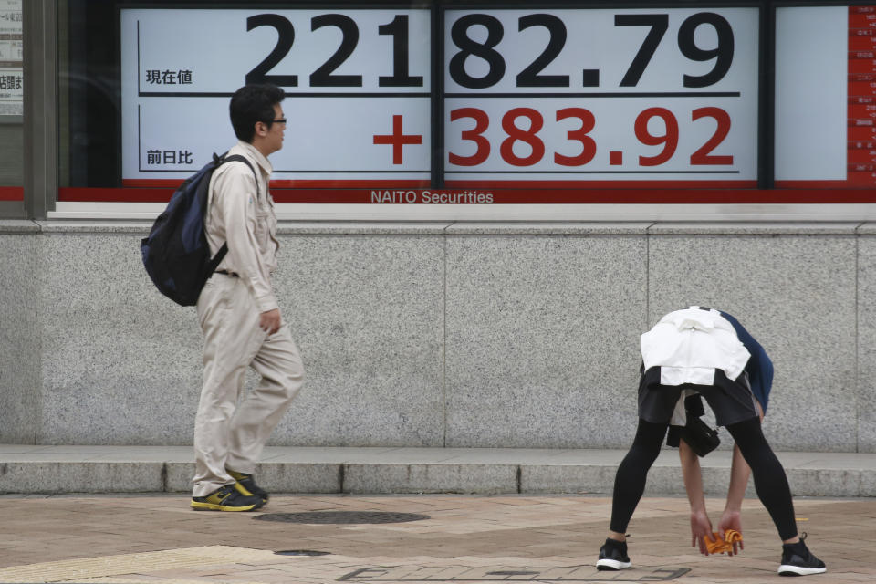 A man stretches in front of an electronic stock board of a securities firm in Tokyo, Tuesday, Oct. 15, 2019. On Tuesday, shares are mixed in Asia after a wobbly day of trading on Wall Street. Japan’s Nikkei 225 index jumped 1.8% as it reopened from a public holiday and investors caught up on the news of a preliminary trade deal between China and the U.S. (AP Photo/Koji Sasahara)