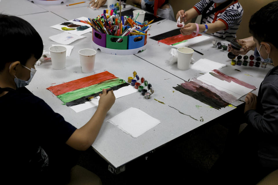 Young Afghan children paint a piece of paper with the colors of the national flag of Afghanistan in an art class at the National Conference Center (NCC), which in recent months has been redesigned to temporarily house Afghan nationals on August 11, 2022 in Leesburg, Virginia.  / Credit: Getty Images