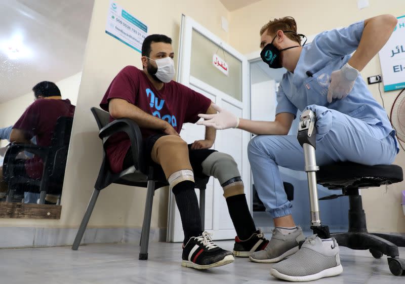 Abdelmawla Ibrahim, a Syrian amputee and physical therapist, talks to a patient at Al-Bab centre for prosthetics in Al-Bab