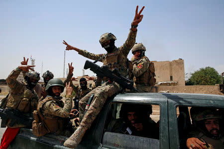 Members of Iraqi forces make a "V" sign as they arrive to take part in a victory celebration after defeating the Islamic State militants and retaking the Grand al-Nuri Mosque in the Old City in Mosul, Iraq July 2, 2017. REUTERS/Erik De Castro