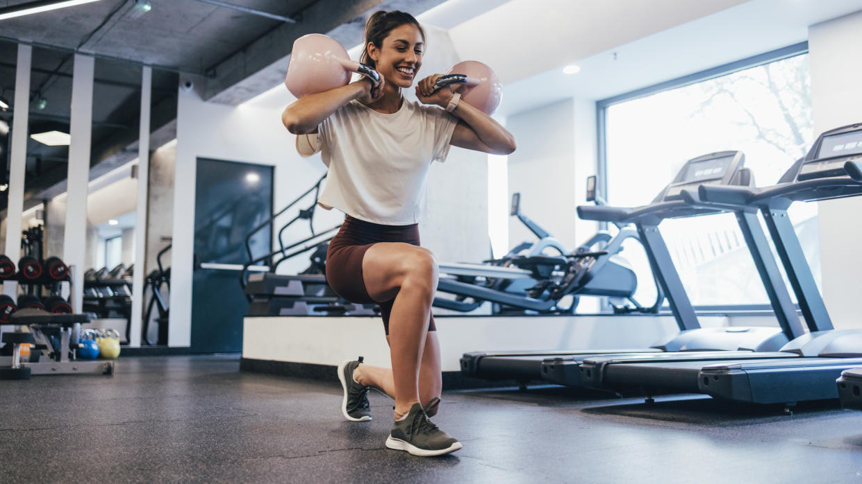  Woman working out with kettlebells in a gym. 