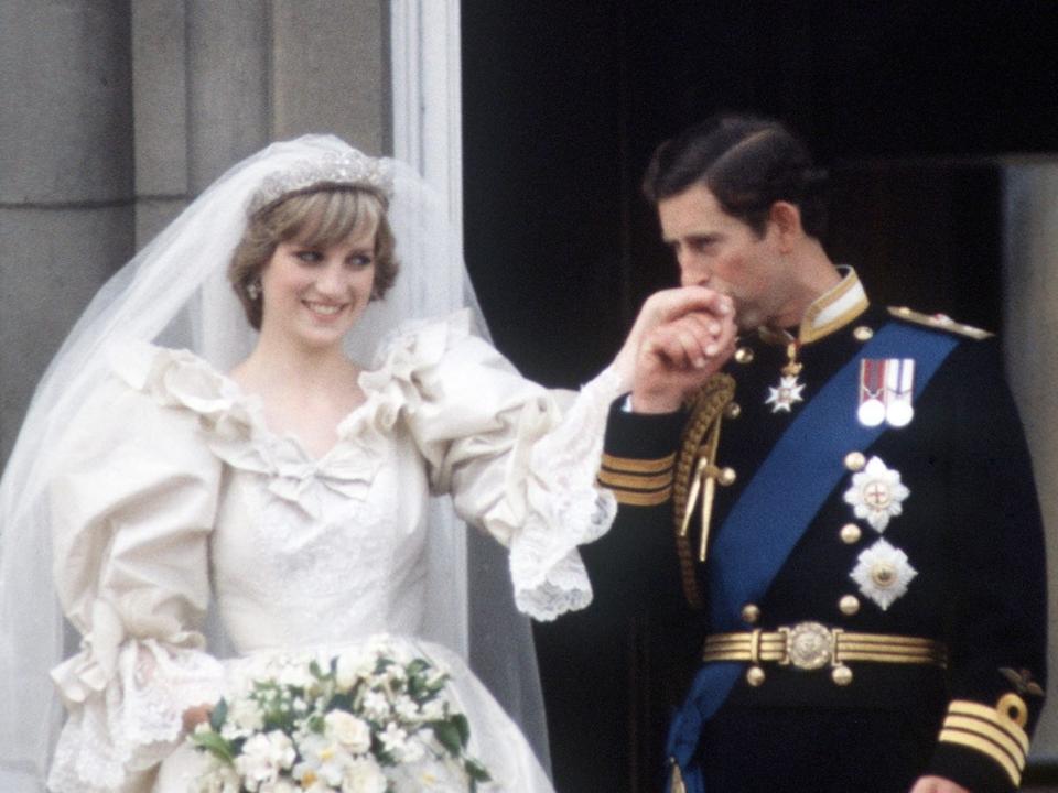prince charles kissing princess diana's hand as they stand on the balcony of buckingham palace