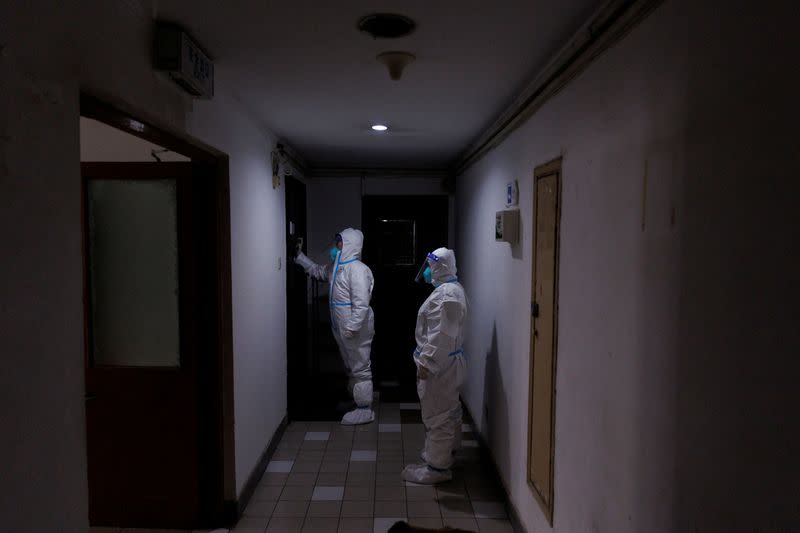 FILE PHOTO: Pandemic prevention workers in protective suits knock on a resident's door in an apartment building that went into lockdown as coronavirus disease (COVID-19) outbreaks continue in Beijing