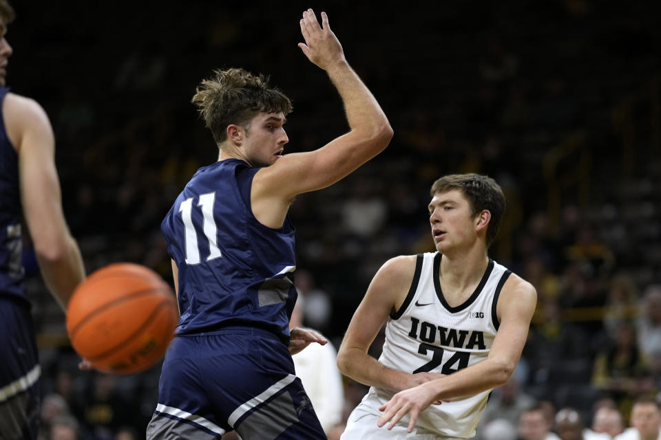 Iowa forward Pryce Sandfort (24) passes around North Florida guard Nate Lliteras (11) during the second half of an NCAA college basketball game, Wednesday, Nov. 29, 2023, in Iowa City, Iowa. Iowa won 103-78. (AP Photo/Charlie Neibergall)