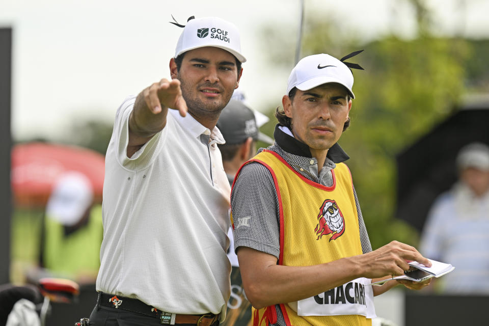 Eugenio Lopez-Chacarra, left, from Spain gestures with his caddy on the 11th hole during LIV Golf Invitational Bangkok 2022 at Stonehill Golf Club in Pathum Thani, Thailand, Saturday, Oct. 8, 2022. (AP Photo/Kittinun Rodsupan)