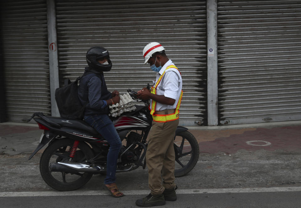 A traffic policemen gives a penalty to a motorist for breaking COVID-19 guidelines during a lockdown imposed to curb the spread of the coronavirus in Hyderabad, India, Saturday, June 12, 2021. (AP Photo/Mahesh Kumar A.)