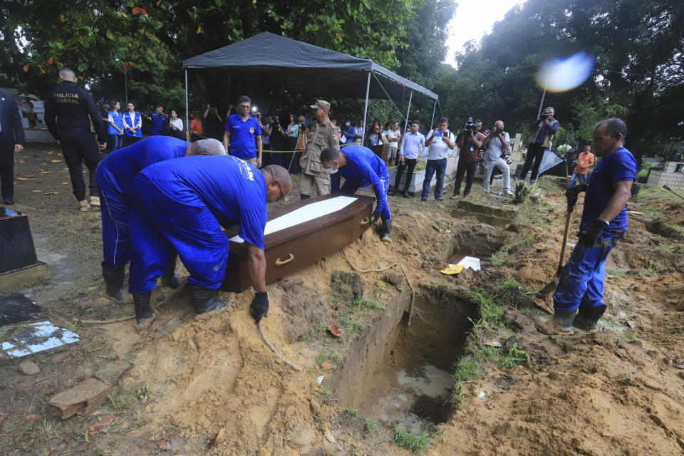 Cemetery workers lower into a grave, a coffin that contains the remains of an unidentified migrant, at the Sao Jorge cemetery, in Belem, Para state, Brazil, Thursday, April 25, 2024. The bodies of nine migrants found on an African boat off the northern coast of Brazil's Amazon region were buried Thursday with a solemn ceremony. (AP Photo/Paulo Santos)