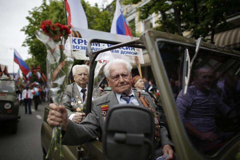 WWII veterans take part in the May Day march in cars decorated with Russian and Crimean flags and posters reading: "Crimea - Russia, Welcome Home" in Simferopol, Crimean capital on Thursday, May 1, 2014. (AP Photo/ Max Vetrov)