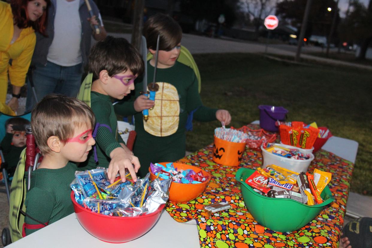 Donovan Masker, 4, Charlie Masker, 7, and Brody Masker, 10, pick out candy during Beggars’ Night in Van Meter on Oct. 30, 2022.