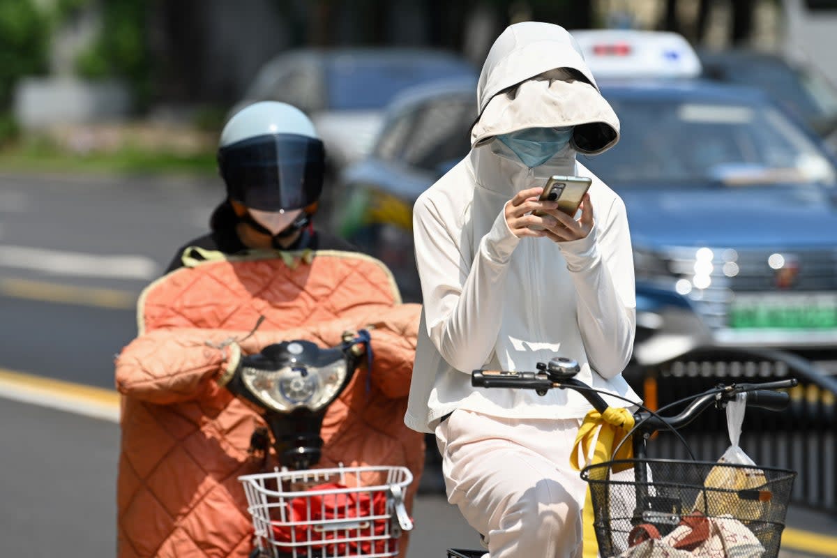 A woman wearing sun protective clothing commutes on a bicycle amid hot weather in Shanghai on Monday  (AFP/Getty )