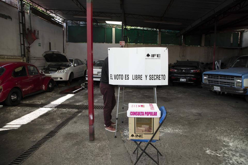 A man casts his during in a non-binding referendum on whether Mexican ex-presidents should be tried for any illegal acts during their time in office, in Mexico City, Sunday, August 1, 2021. (AP Photo/Christian Palma)