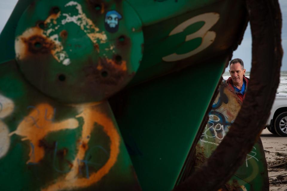 Jace Tunnell, a marine biologist and community engagement director with Harte Research Institute, looks at a buoy stranded on the beach at Padre Island National Seashore on Tuesday, March 19, 2024, in Corpus Christi, Texas. Tunnell said the buoy was likely a channel marker.