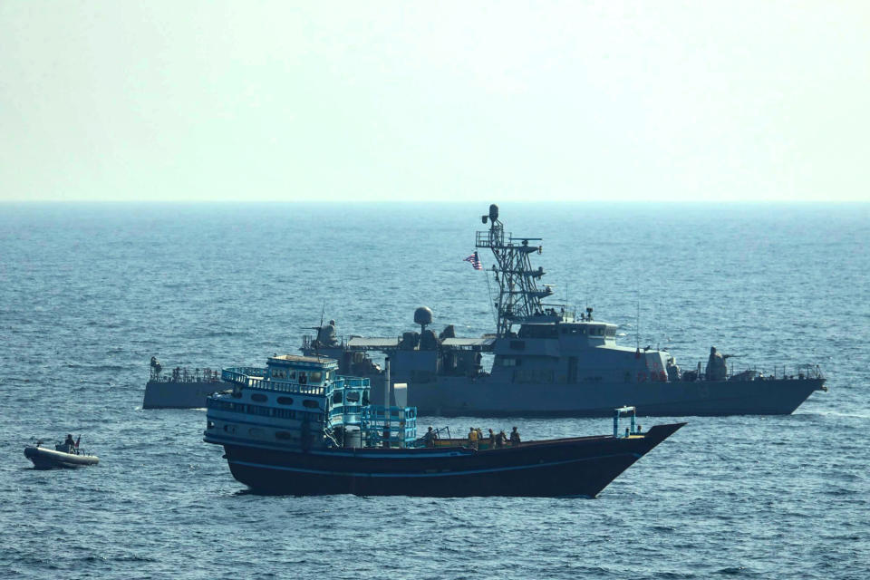 This photo released by the U.S. Navy, shows U.S. service members conduct a boarding on a stateless fishing vessel transiting international waters in the Gulf of Oman as a rigid-hull inflatable boat and patrol coastal ship USS Chinook (PC 9) sail nearby, Tuesday, Jan. 18, 2022. The U.S. Navy announced Sunday, Jan. 23 that it seized the boat in the Gulf of Oman carrying fertilizer used to make explosives that was caught last year smuggling weapons to Yemen. (U.S. Navy via AP)