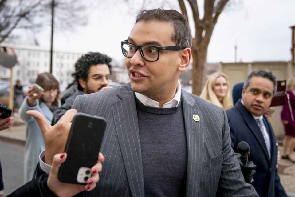 Rep. George Santos walking outside amid reporters.