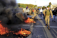 A Lebanese soldier walks past burning tires that were set on fire by protesters to block a highway that leads to Beirut's international airport, in Beirut, Lebanon, Tuesday, March 2, 2021. Scattered protests broke out in different parts of Lebanon Tuesday after the Lebanese pound hit a record low against the dollar on the black market, a sign of the country's multiple crises deepening with no prospects for a new Cabinet in the near future. (AP Photo/Hussein Malla)