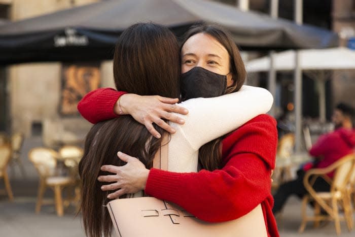 abrazo de dos amigas con mascarilla