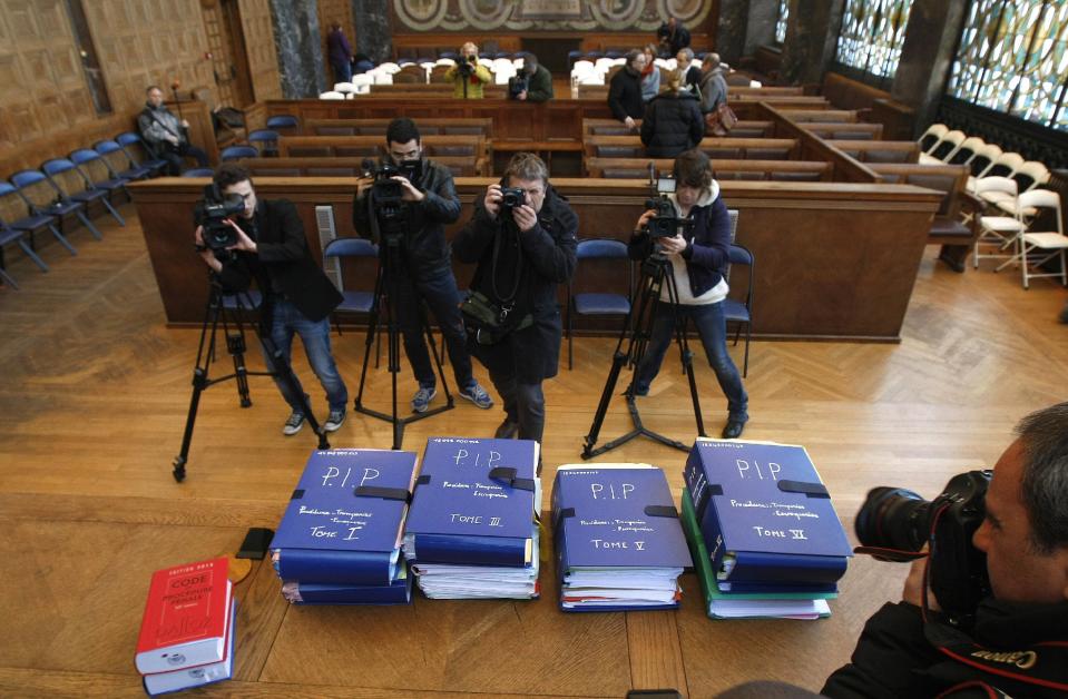 Reporters focus on documents concerning the Poly Implant Prothese (PIP) breast implant trial, displayed in the courthouse in Marseille, southern France, Monday, Dec. 9, 2013. A court decides Tuesday whether Jean-Claude Mas, founder of the defunct PIP silicone breast implant company, is guilty of aggravated fraud by making tens of thousands of defective implants using industrial grade silicone, and selling them worldwide. The tribunal is expected to decide whether the German product-testing firm TUeV Rheinland was a victim of deception by Jean-Claude Mas or could be held responsible by failing to properly check the implants. More than 125,000 women received the implants until sales ended in March 2010. (AP Photo/Claude Paris)