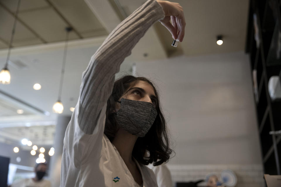 A medical worker prepares a vial of the Pfizer coronavirus vaccine at Clalit Health Service's vaccination center in the Cinema City complex in Jerusalem, Wednesday, Sept. 22, 2021. Israel is pressing ahead with its aggressive campaign of offering coronavirus boosters to almost anyone over 12 and says its approach was further vindicated by a U.S. decision to give the shots to older patients or those at higher risk. (AP Photo/Maya Alleruzzo)