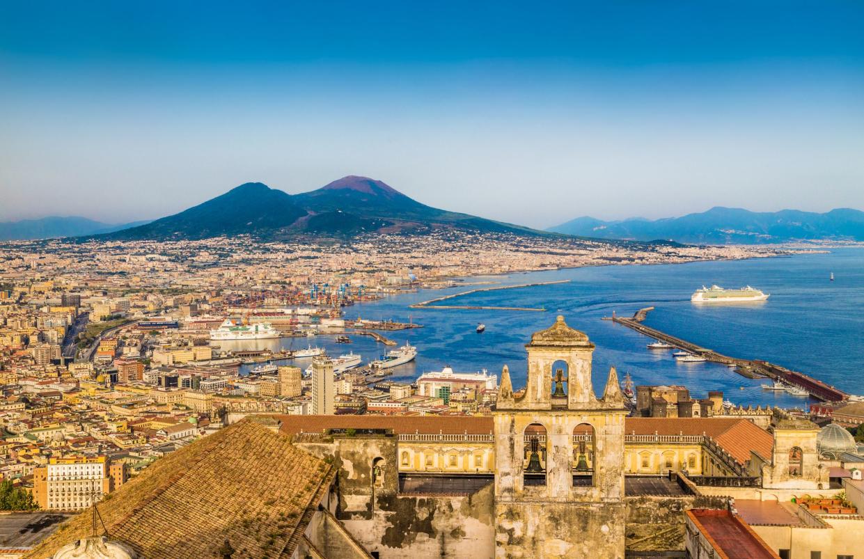 Scenic picture-postcard view of the city of Napoli (Naples) with famous Mount Vesuvius in the background in golden evening light at sunset, Campania, Italy.