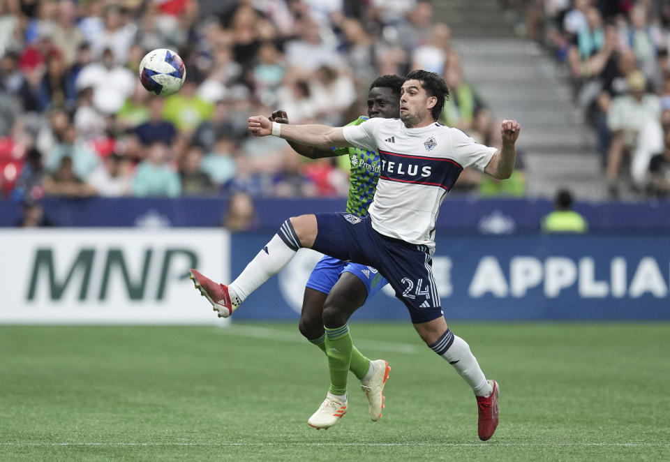 Vancouver Whitecaps' Brian White, front, and Seattle Sounders' Yeimar Gomez vie for the ball during the first half of an MLS soccer match in Vancouver, British Columbia on Saturday, May 20, 2023. (Darryl Dyck/The Canadian Press via AP)