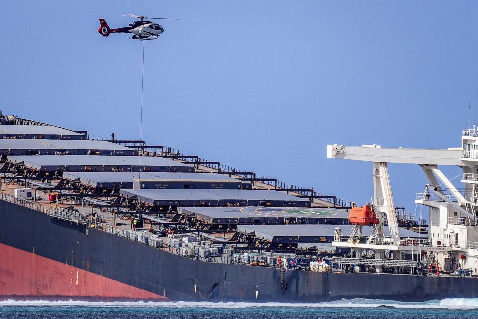 A helicopter hovers over the vessel MV Wakashio that ran aground and caused oil leakage in southeast Mauritius.