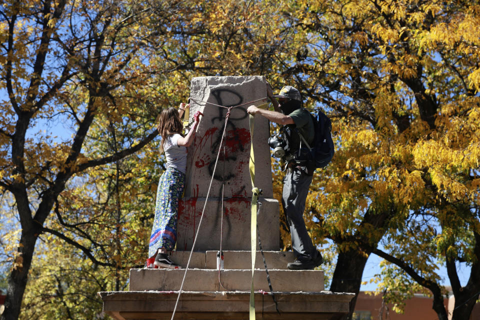 FILE - In this Oct. 12, 2020, file photo, demonstrators secure a rope around the centerpiece of a solid stone obelisk before tearing it down in Santa Fe, N.M. At least 160 Confederate symbols were taken down or moved from public spaces in 2020. That's according to a new count the Southern Poverty Law Center shared with The Associated Press. (AP Photo/Cedar Attanasio, File)