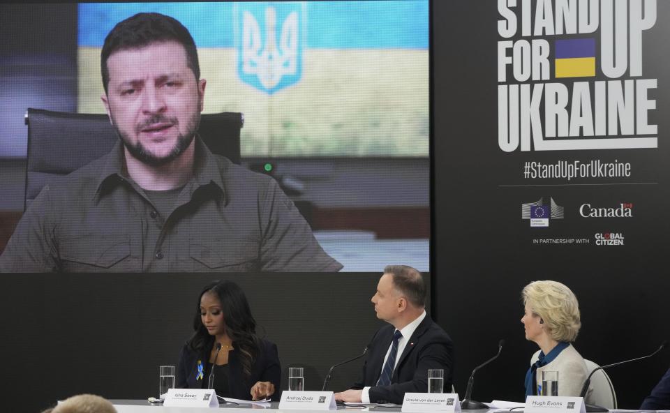 European Commission head Ursula von der Leyen, right, and Poland's President Andrzej Duda ,center, watching Ukraine's President Volodymyr Zelensky on a screen at the main event of the "Stand Up for Ukraine" global campaign for pledging funds for Ukraine and its refugees, at the Palace on the Water, in Warsaw, Poland, on Saturday, April 9, 2022. Launched by the European Commission and Canada's Prime Minister Justin Trudeau, the event was joined remotely by Trudeau and by Ukraine's President Volodymyr Zelensky. (AP Photo/Czarek Sokolowski)