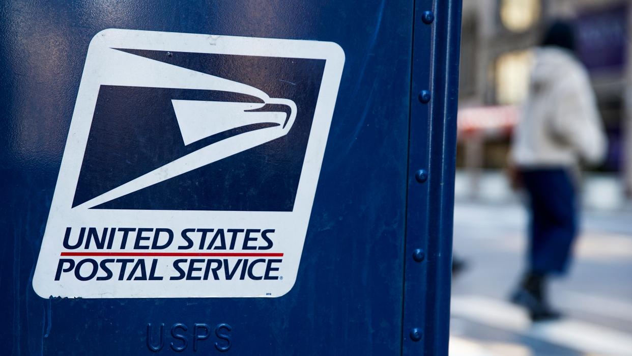 A USPS logo is seen on a mailbox