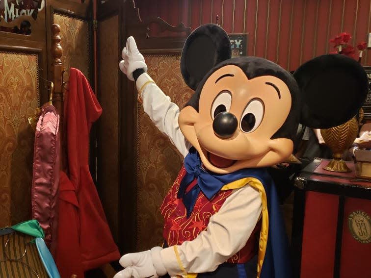mickey gesturing toward robes in his meet and greet area at disney world